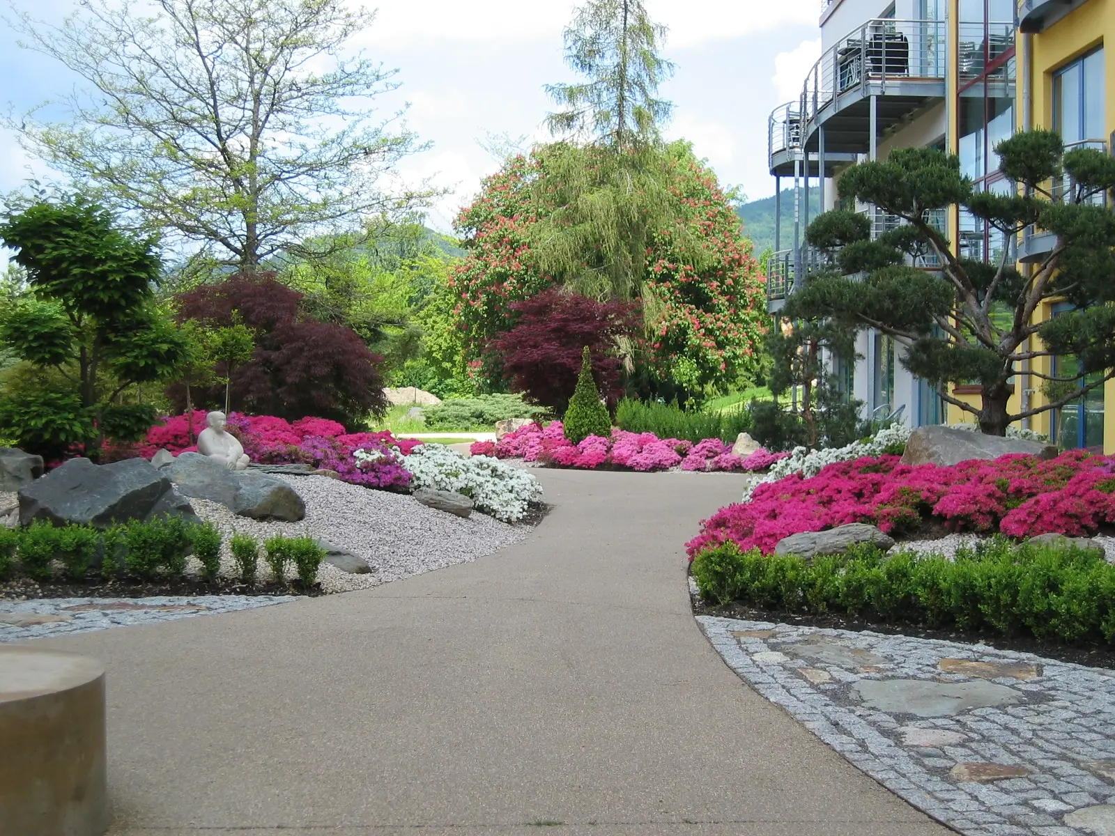 Großzügige Außenanlage mit Rhododendren und Formschnitt