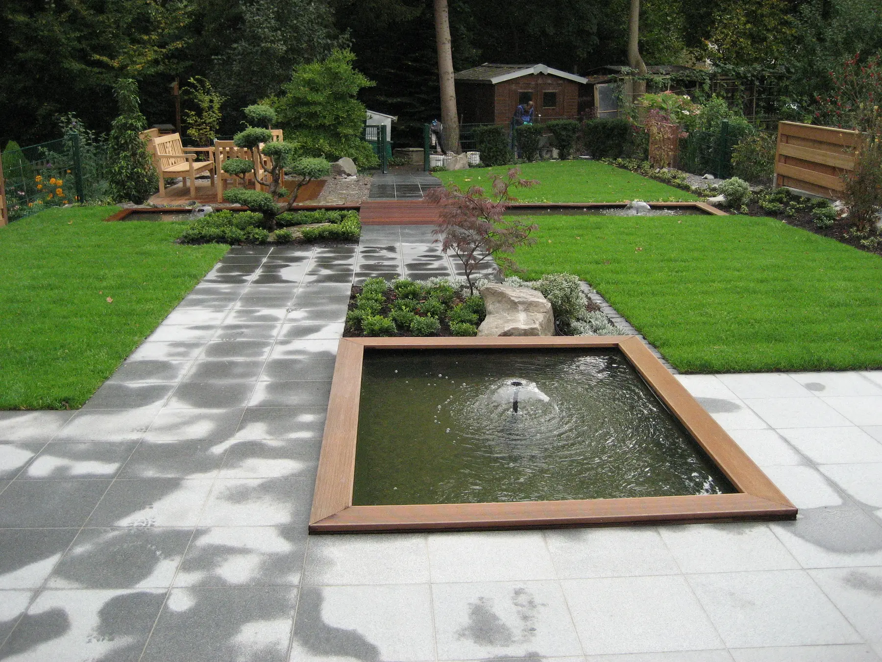 Geradliniges Wasserbecken als Achse in einem modernen Garten